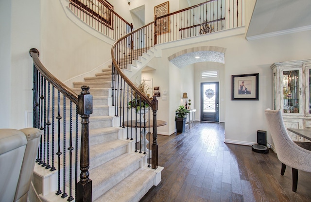 entrance foyer with arched walkways, a high ceiling, dark wood-type flooring, and baseboards