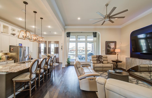 living room with ceiling fan with notable chandelier, dark wood finished floors, recessed lighting, crown molding, and baseboards