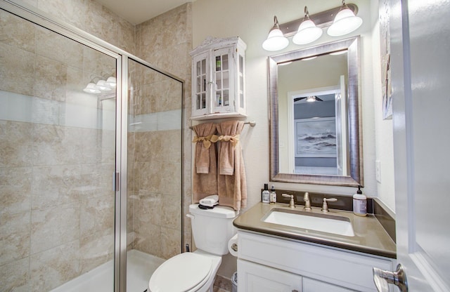 bathroom with a shower stall, toilet, and vanity