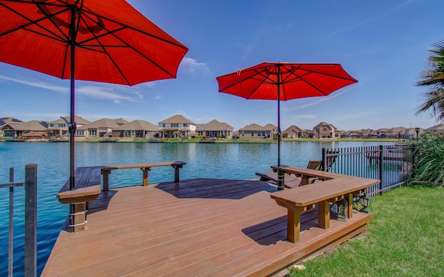 view of dock featuring a residential view, fence, and a water view