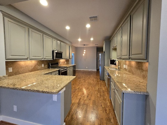 kitchen featuring visible vents, a sink, dark wood-style floors, stainless steel appliances, and baseboards