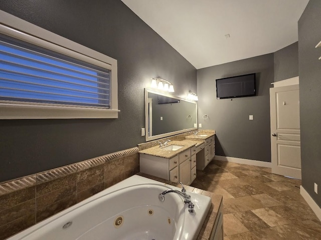 full bathroom with vanity, vaulted ceiling, baseboards, and a whirlpool tub