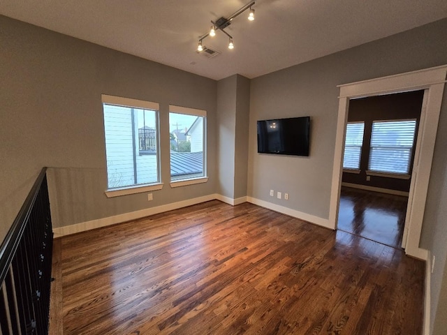 unfurnished room featuring visible vents, baseboards, wood finished floors, and rail lighting