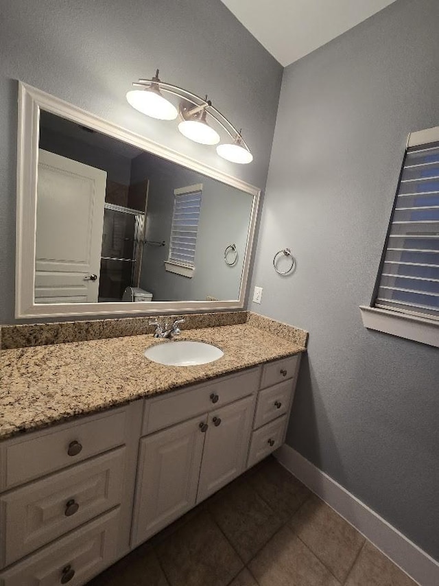 bathroom with tile patterned floors, baseboards, a stall shower, and vanity