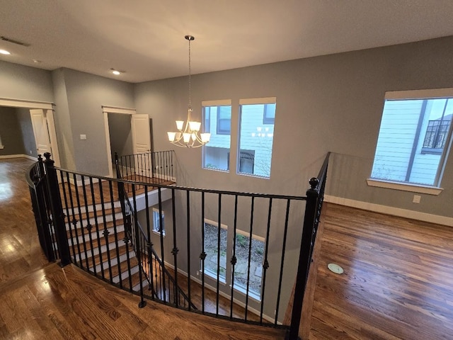 staircase with a chandelier, visible vents, plenty of natural light, and wood finished floors