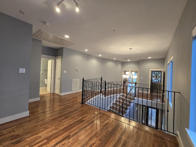 hall featuring wood finished floors, attic access, an upstairs landing, and baseboards