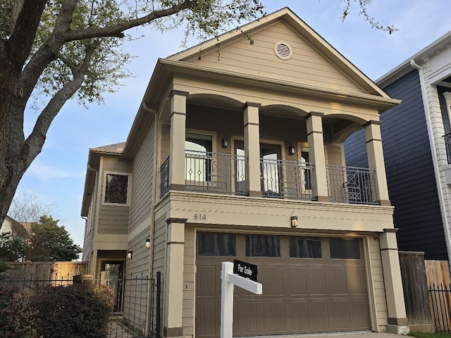 view of front of property with a balcony, an attached garage, and fence