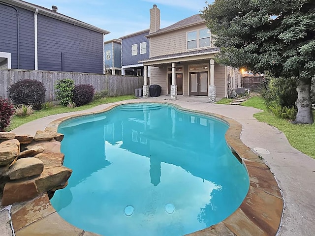 view of pool featuring central air condition unit, a fenced in pool, french doors, and a fenced backyard