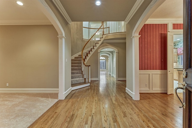 entrance foyer featuring arched walkways, crown molding, ornate columns, and wood finished floors