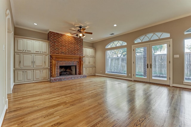 unfurnished living room featuring a ceiling fan, baseboards, light wood finished floors, a fireplace, and ornamental molding