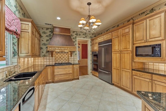 kitchen with wallpapered walls, a chandelier, custom exhaust hood, black appliances, and a sink