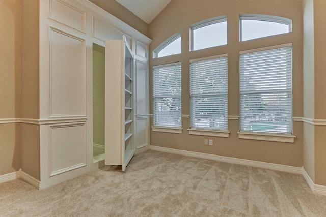 interior space featuring vaulted ceiling, baseboards, and light carpet