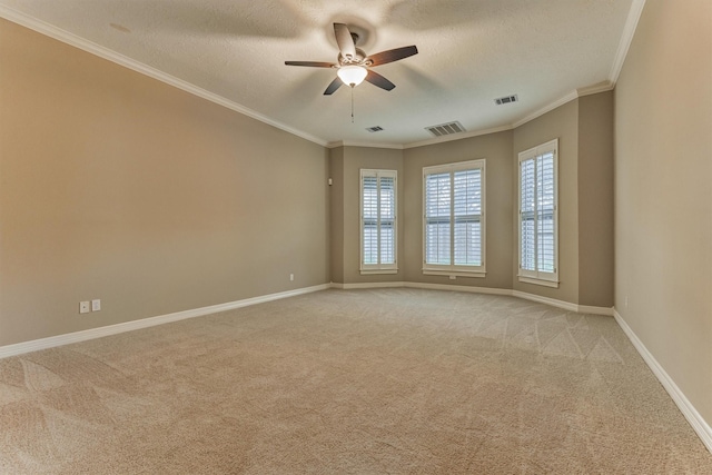 spare room with visible vents, crown molding, baseboards, ceiling fan, and light carpet