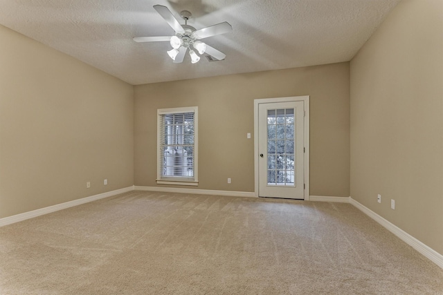 spare room featuring a wealth of natural light, light colored carpet, baseboards, and a ceiling fan