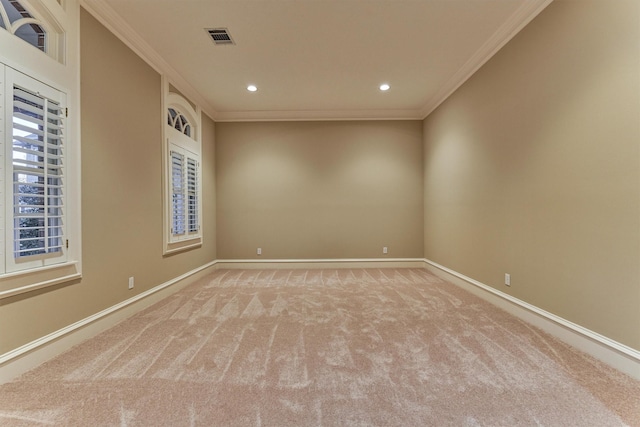 spare room with visible vents, baseboards, light colored carpet, and crown molding