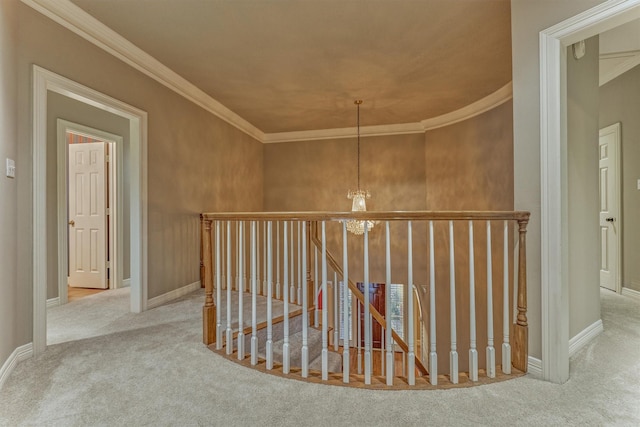 hall with baseboards, carpet floors, an upstairs landing, ornamental molding, and an inviting chandelier