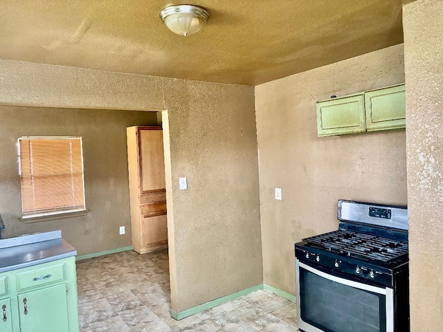 kitchen with baseboards, stainless steel range with gas cooktop, and green cabinetry