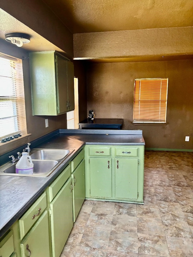 kitchen featuring green cabinets, baseboards, and a sink