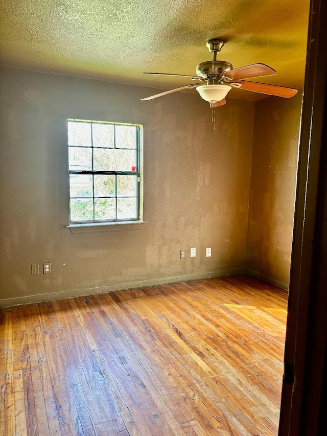 empty room with a ceiling fan, wood-type flooring, and a textured ceiling