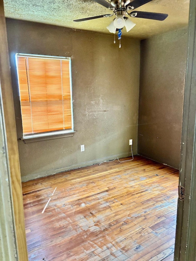 unfurnished room featuring a textured wall, a textured ceiling, ceiling fan, and hardwood / wood-style flooring