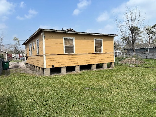 view of home's exterior with a lawn and fence