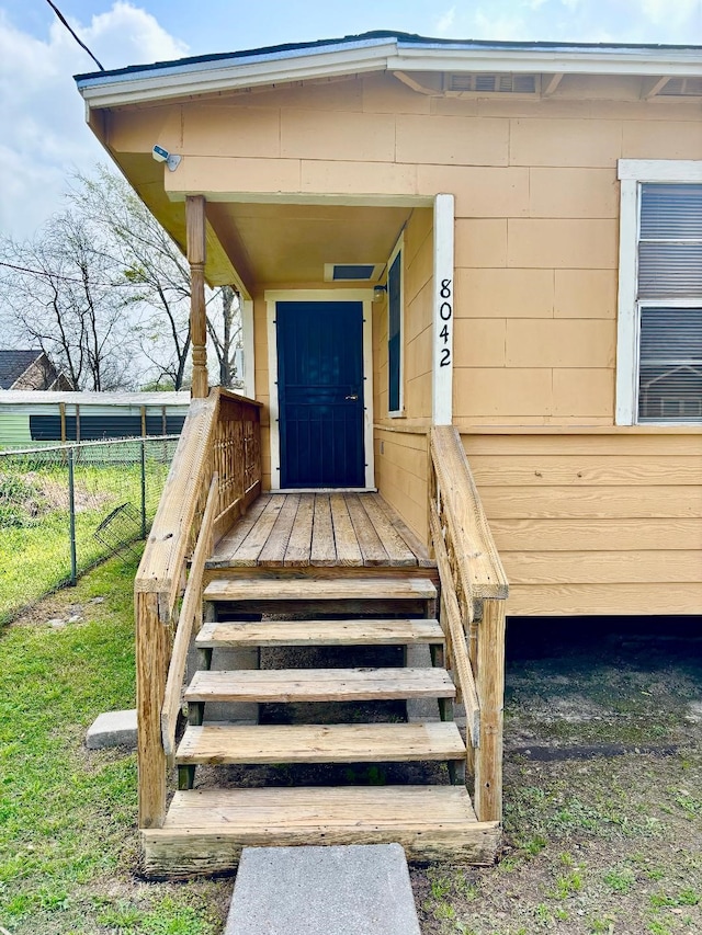 entrance to property featuring concrete block siding and fence