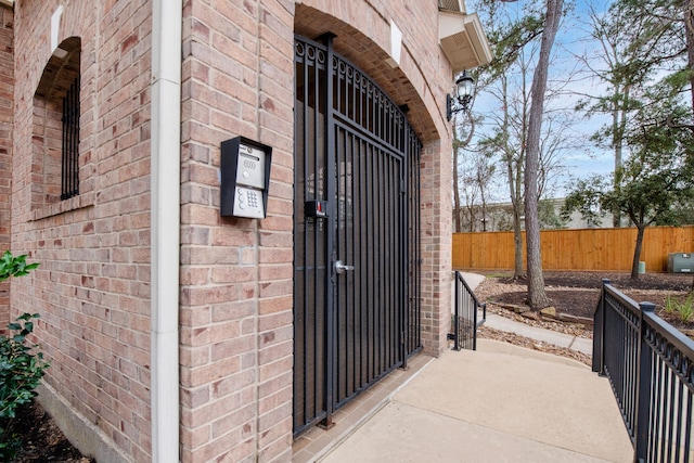 property entrance featuring brick siding and fence