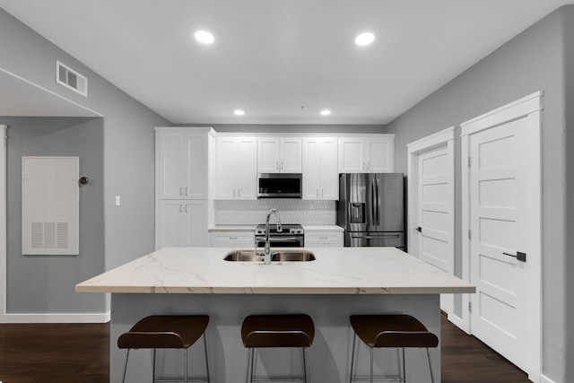 kitchen with a breakfast bar area, visible vents, white cabinets, and stainless steel appliances