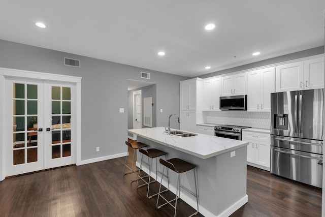 kitchen with visible vents, dark wood-type flooring, a sink, light stone counters, and appliances with stainless steel finishes