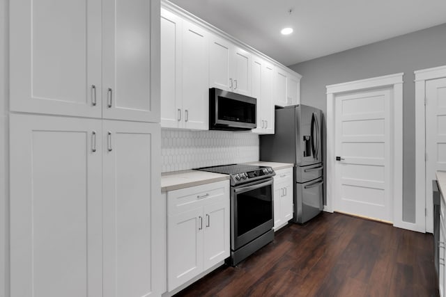 kitchen with dark wood finished floors, stainless steel appliances, decorative backsplash, light countertops, and white cabinets