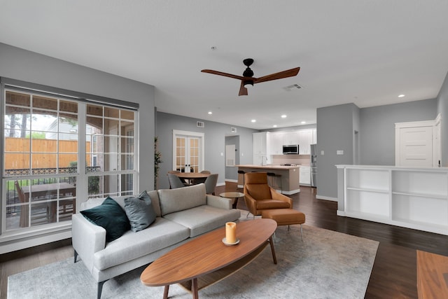 living room featuring visible vents, baseboards, ceiling fan, recessed lighting, and dark wood-style flooring