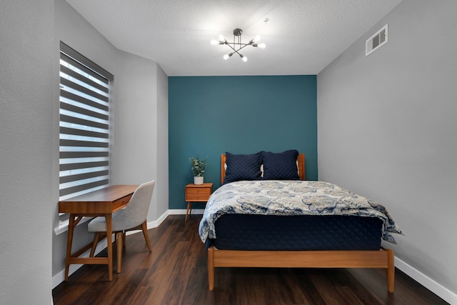 bedroom with wood finished floors, visible vents, baseboards, an inviting chandelier, and a textured ceiling