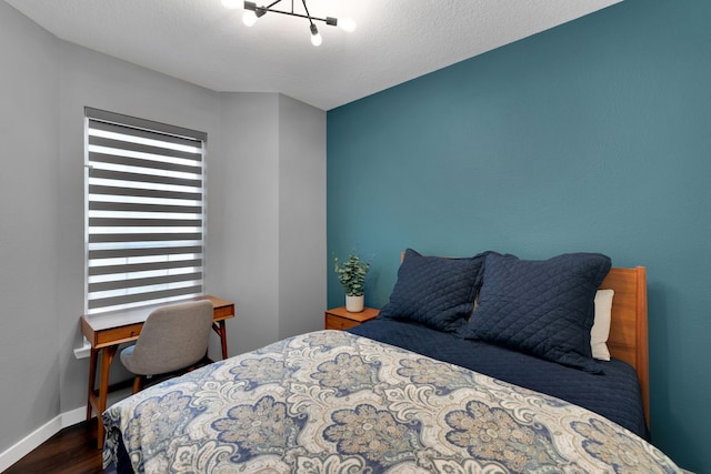 bedroom with baseboards, a textured ceiling, and dark wood-style flooring