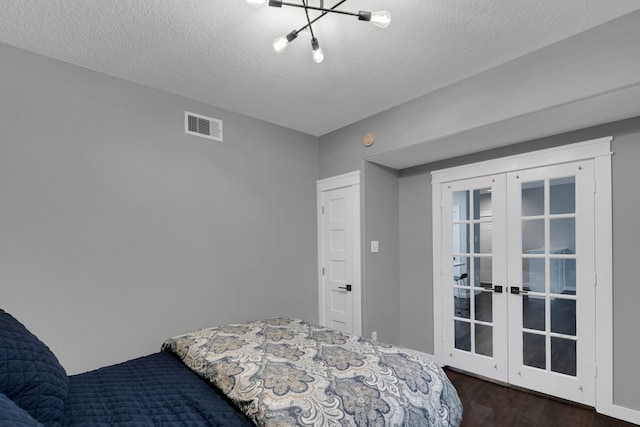 bedroom featuring french doors, a textured ceiling, visible vents, and dark wood-style floors