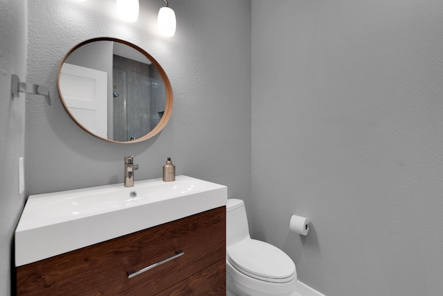 bathroom with toilet, vanity, and a textured wall