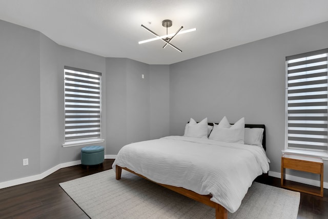 bedroom featuring a chandelier, baseboards, and wood finished floors