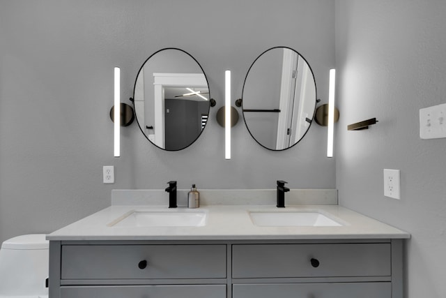 bathroom featuring double vanity, toilet, and a sink