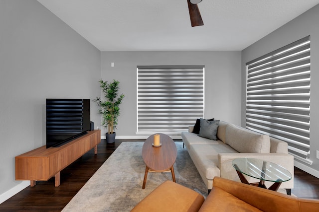 living room featuring baseboards, dark wood-style flooring, and ceiling fan