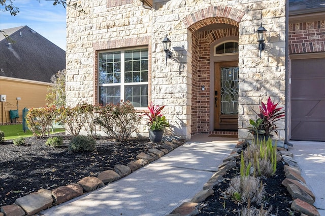 view of exterior entry featuring stone siding and brick siding