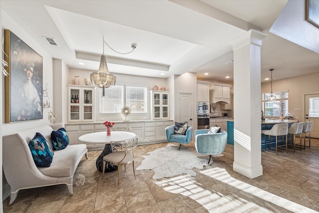 living room with visible vents, baseboards, a tray ceiling, recessed lighting, and a notable chandelier