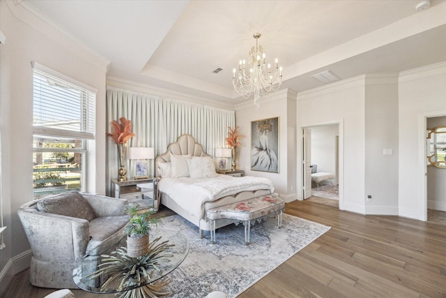 bedroom featuring wood finished floors, baseboards, a tray ceiling, crown molding, and a chandelier