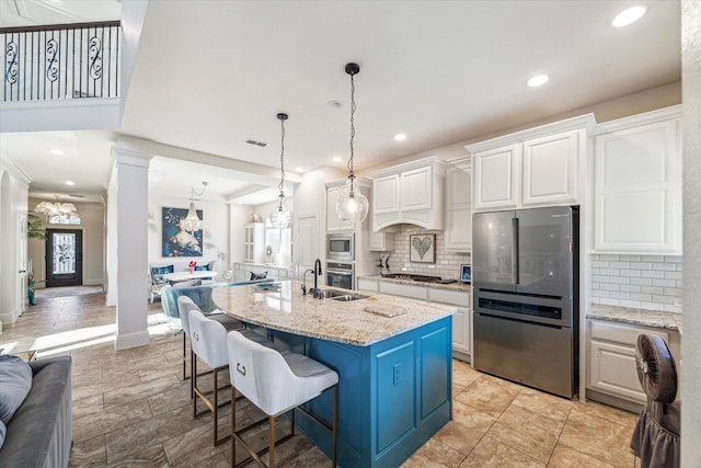 kitchen with a breakfast bar area, white cabinets, appliances with stainless steel finishes, open floor plan, and backsplash