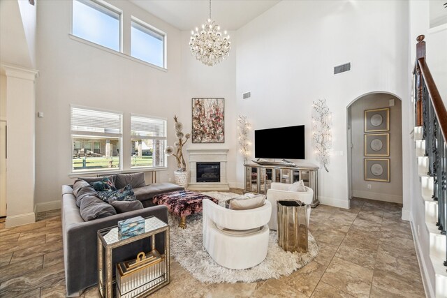 living room featuring arched walkways, visible vents, plenty of natural light, and a glass covered fireplace