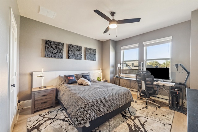 bedroom with light wood-style flooring, a ceiling fan, visible vents, and baseboards