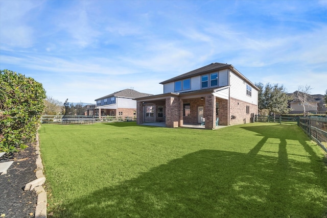 rear view of property with brick siding, a yard, a patio, and a fenced backyard