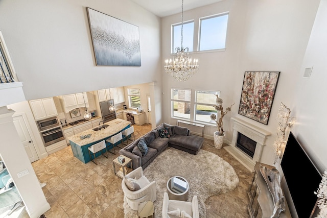 living room with a high end fireplace, a notable chandelier, plenty of natural light, and a high ceiling