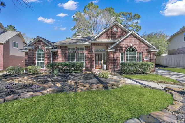 view of front facade featuring brick siding, a front lawn, and fence