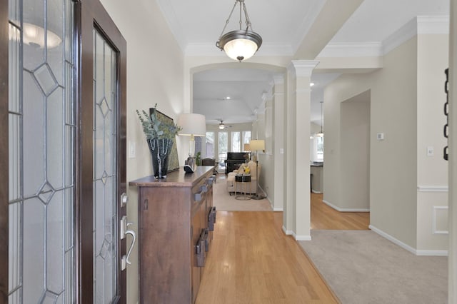 entryway with ornamental molding, a ceiling fan, light wood-style floors, baseboards, and ornate columns