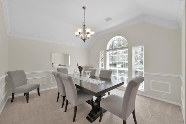 dining area with light carpet, a chandelier, a decorative wall, and vaulted ceiling