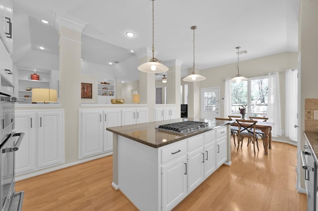 kitchen featuring white cabinets, stainless steel appliances, a center island, and light wood-style floors